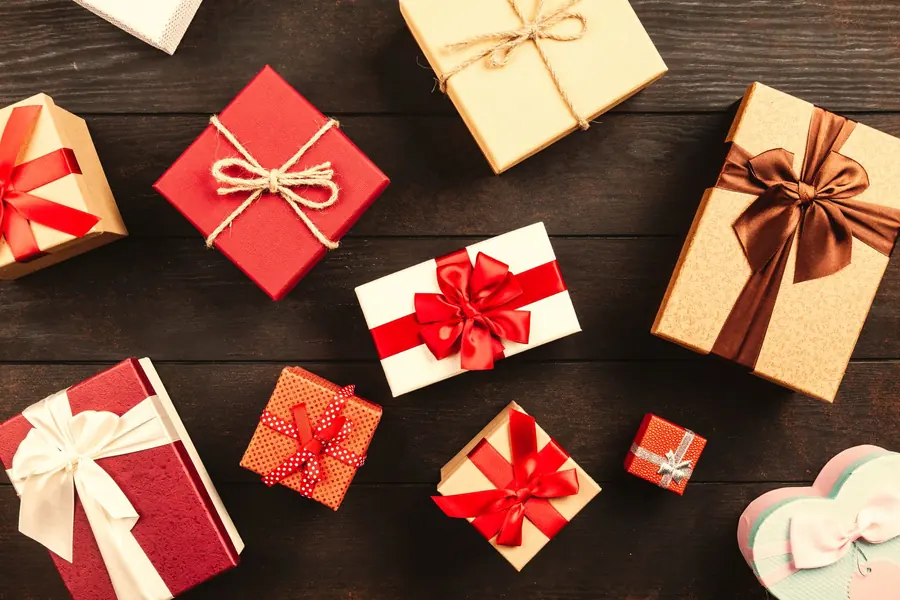 Wrapped gift boxes with red and gold ribbons on a dark wooden table